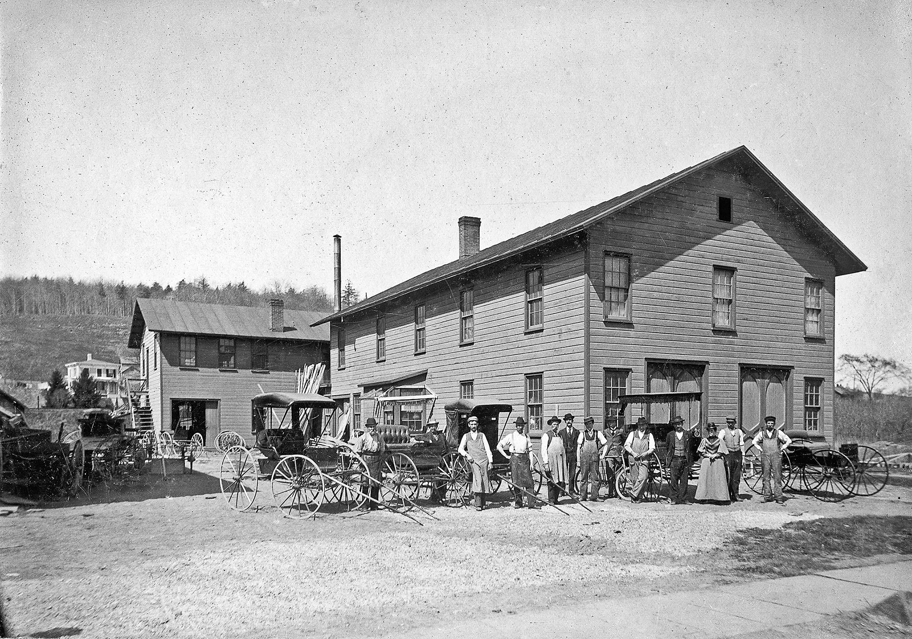 Historic photo of workers and horse-drawn carriages outside the Altamont Carriage Works